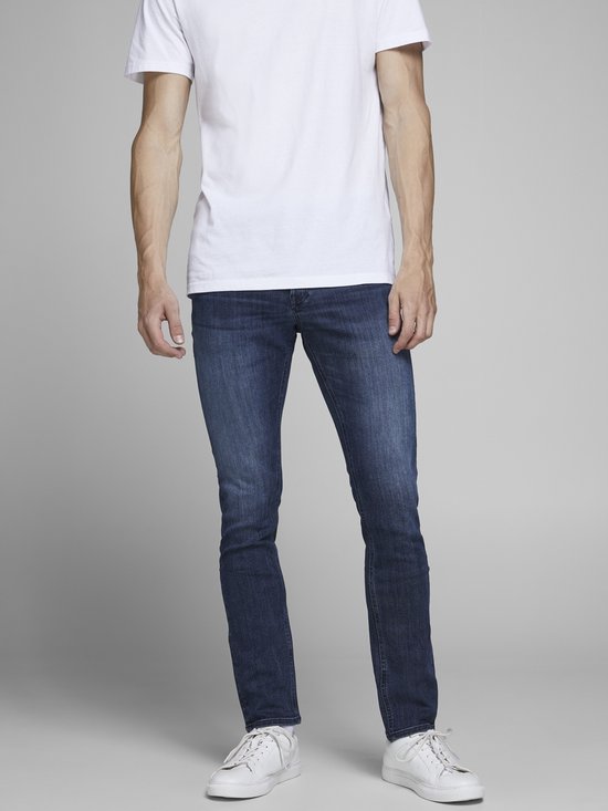 Man in witte T-shirt en donkerblauwe slim fit jeans, voorkant.