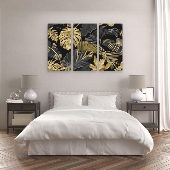 Drieluik met gouden en zwarte tropische bladeren, boven een bed in slaapkamer.