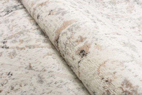 Gros plan détaillé sur la texture pelucheuse d'un tapis beige avec des motifs délavés.