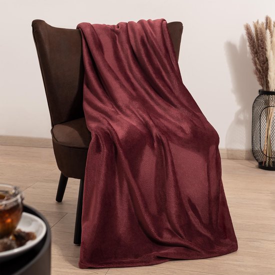 Bordeauxrode fleecedeken over een bruine fauteuil.