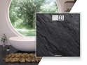 Donkergrijze, leisteen-look digitale weegschaal met een '0.0' weergave in een luxe badkamer met badkuip.