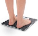 Voeten op een donkergrijze, leisteen-look digitale weegschaal die 59,3 kg weergeeft.