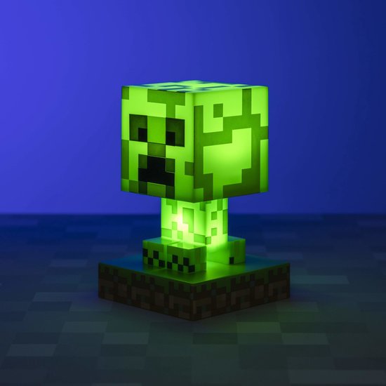 Een felgroene Minecraft Creeper-lamp, gloeiend met intern licht, staand op een gras- en aarde-voetstuk.