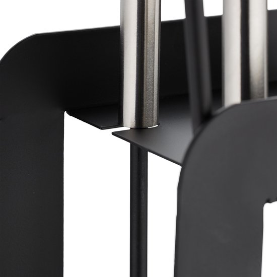 Close-up van de zilverkleurige handvatten van het zwarte haardgereedschap.