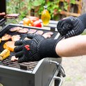 Hand met zwarte, hittebestendige handschoen met siliconen noppen, stel de handschoen bij op de barbecue.