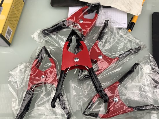 Vijf rode zeilklemmen van 15 cm lang met zwarte handvatten, verpakt in plastic.