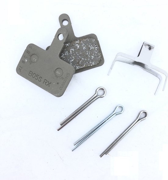 Deux plaquettes de frein Shimano B05S RX à surface rugueuse, un support métallique et trois goupilles argentées.