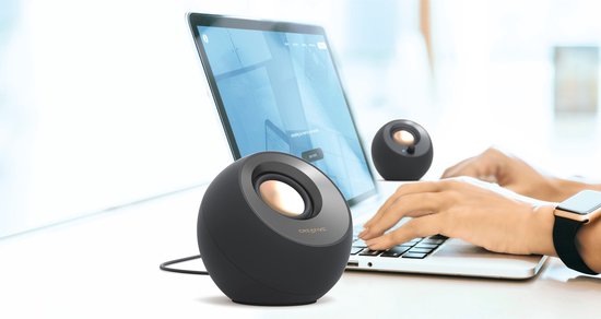 Twee zwarte speakers naast een laptop, bediend door een persoon.