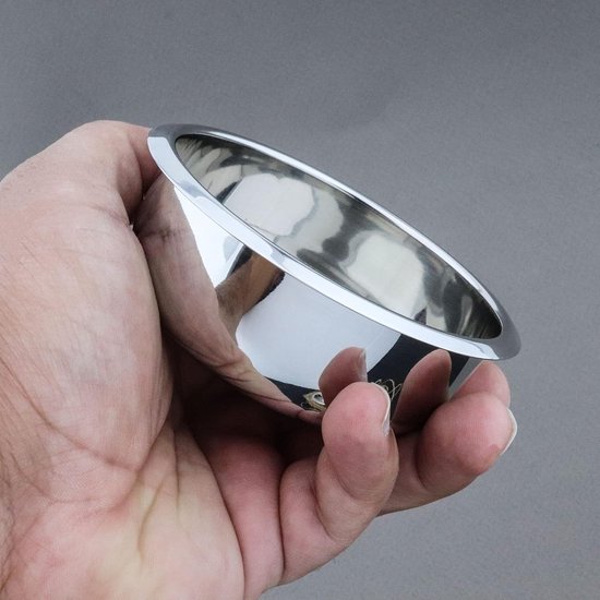 Een hand die een glanzende, zilverkleurige metalen scheerkom vasthoudt.