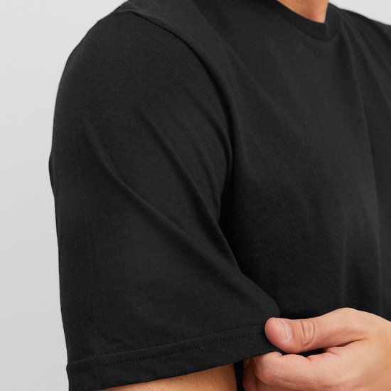 Een close-up van een man die de zoom van een zwart T-shirt oprolt.