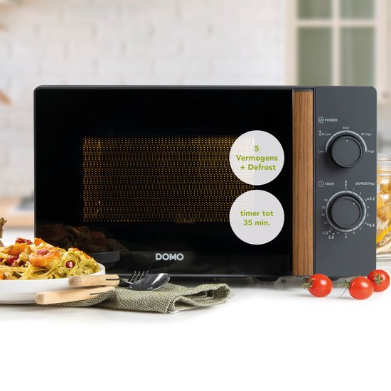 Grijze DOMO magnetron met houtlook handvat, naast een bord pasta. Informatie: 5 vermogens + ontdooien, timer tot 35 min.