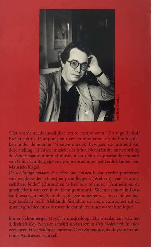 Zwart-witfoto van een man met bril en overhemd met reverskraag, staand voor een piano.