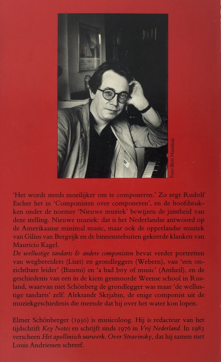 Zwart-witfoto van een man met bril en overhemd met reverskraag, staand voor een piano.
