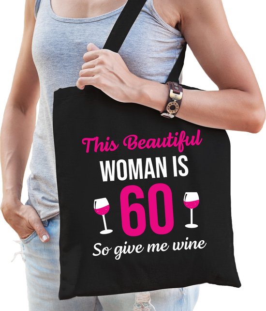 Sac noir avec le texte 'This Beautiful WOMAN IS 60 So give me wine' en lettres roses et blanches.