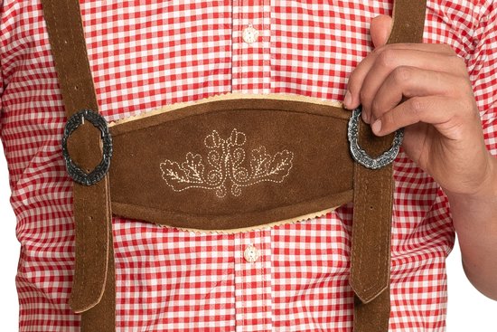 Détail de la culotte de leder brune avec motifs floraux brodés et boucles métalliques sur les bretelles.