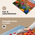 Een hand die een kookplaatbeschermer met bloemenprint schoonmaakt, vuil- en waterafstotend.