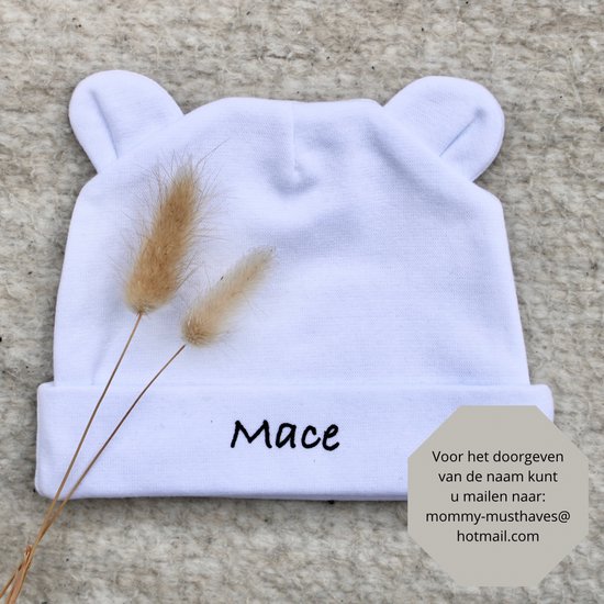 Witte baby muts met oortjes en de naam 'Mace'. Tekst in hoek: 'Voor het doorgeven van de naam kunt u mailen naar: mommy-musthaves@hotmail.com'.