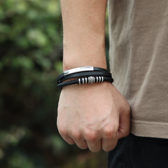 Zwarte leren armband met RVS accenten, gedragen om een pols.