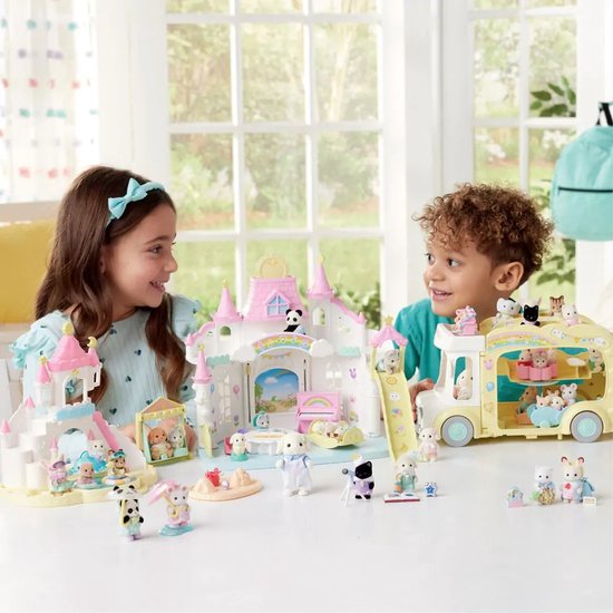 Kinderen spelen met Sylvanian Families speelgoed, waaronder een kasteel en een speelgoedbus.