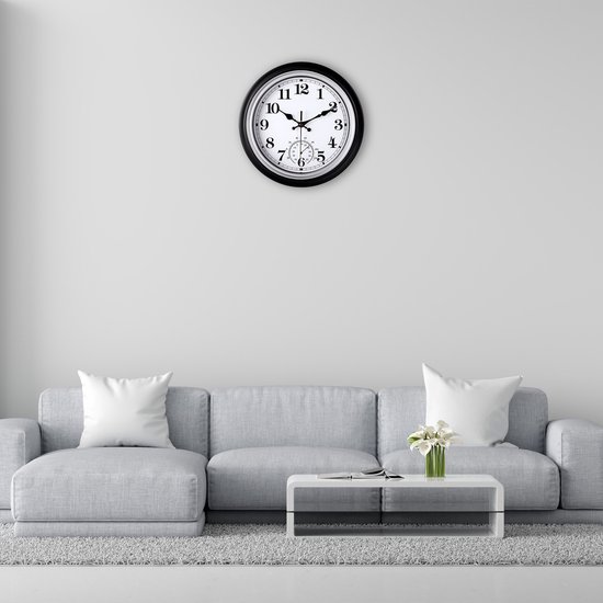 Zwarte wandklok met witte wijzerplaat en thermometer, 30 cm, aan de muur boven een bank
