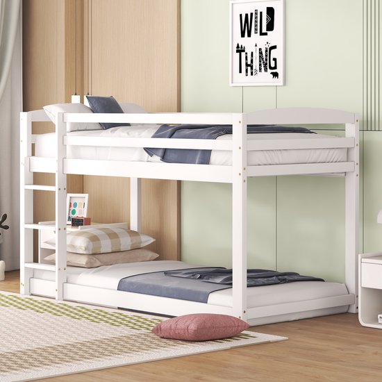 Wit dennenhouten stapelbed opgemaakt met blauwe en witte dekens en kussens, met opbergplank aan de linker ladder.