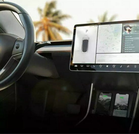 Interieur van Tesla Model 3 met groot touchscreen en dubbele draadloze telefoonoplader met twee opgeladen telefoons.