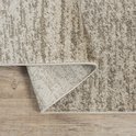 Tapis beige avec un subtil motif quadrillé, bord retourné sur parquet.