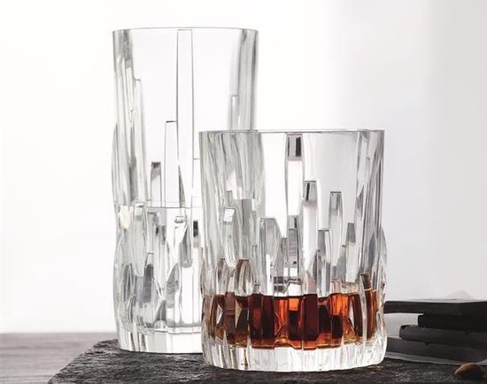 Een laag kristallen glas met amberkleurige vloeistof en een hoger glas, beide met verticale lijnen.
