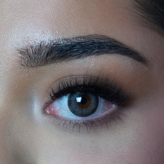 Close-up van een oog met een grijze gekleurde contactlens en lange wimpers.