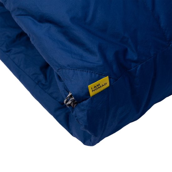 Detail van de donkerblauwe slaapzak met opgestikte gele 'I AM NOMAD' label.