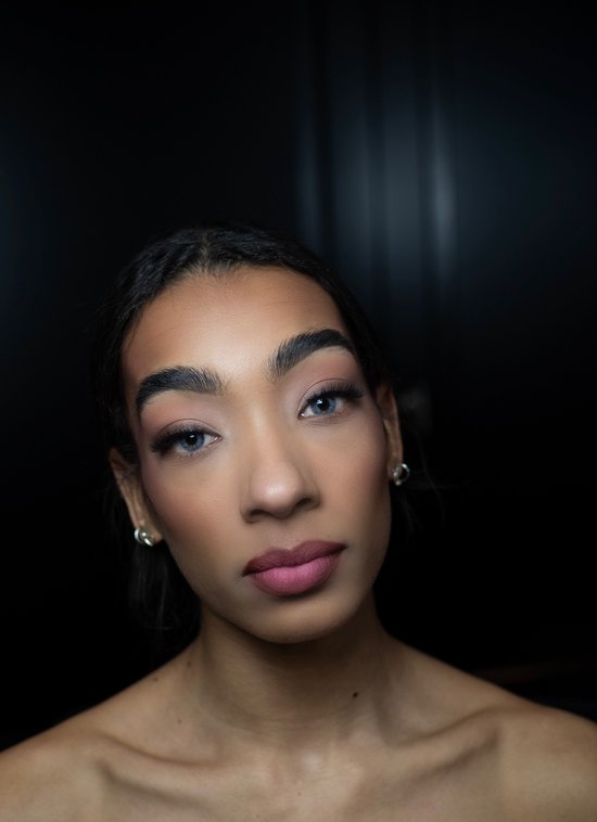 Model met lichtblauwe contactlenzen en make-up. Zilveren oorbellen.