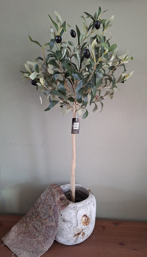 Kunstolijfboom met groene bladeren en zwarte olijven in een verweerde pot.