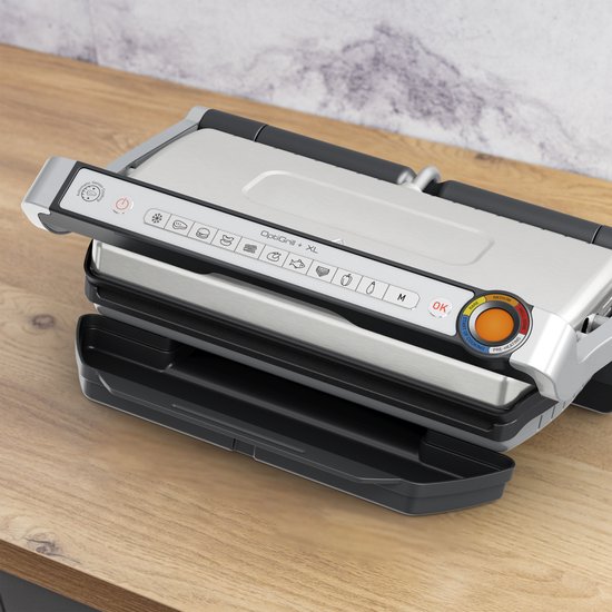 Gesloten Tefal contactgrill op een houten aanrecht. Het bedieningspaneel heeft iconen en een kleurindicator.