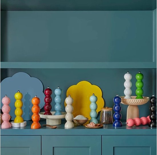 Grote collectie van gestapelde peper- en zoutmolens in diverse felle kleuren op een blauwe plank.
