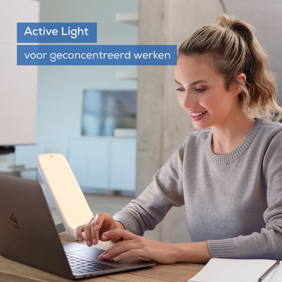 Vrouw met laptop verlicht door witte Beurer daglichtlamp, 'Active Light' voor geconcentreerd werken.