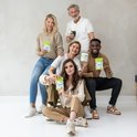 Vijf personen poseren met potjes 'Collageen Premium'. Twee mannen en drie vrouwen, diverse leeftijden en etniciteit.
