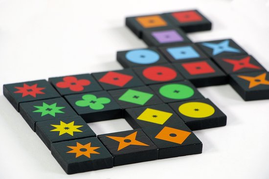 Qwirkle speelstukken met diverse symbolen in verschillende kleuren, gerangschikt op een witte achtergrond.