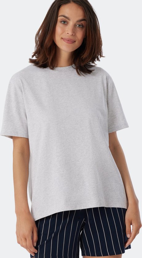 Une femme porte un t-shirt gris chiné à manches courtes et un pantalon à rayures bleu foncé.
