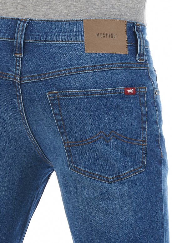 Achterkant van blauwe spijkerbroek met bruin leren Mustang label en rode paard logopatch.