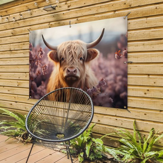 Schotse hooglander met bloemen op een houten schutting, naast een zwarte stoel.