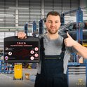 Monteur met jumpstarter koffer en duim omhoog in werkplaats.