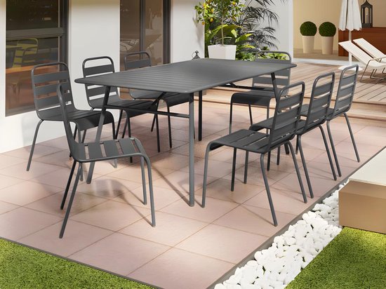 Table de jardin rectangulaire en métal gris foncé avec huit chaises sur une terrasse carrelée.