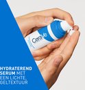 Handen die CeraVe Hydrating Hyaluronic Acid Serum op een vingertop pompen. Tekst: "HYDRATEREND SERUM MET EEN LICHTE, GELTEXTUUR".