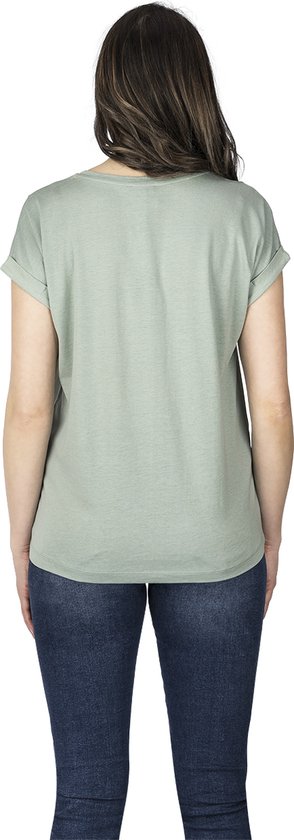 Achterkant vrouw met lichtgroene effen top met opgerolde mouwen en jeans.