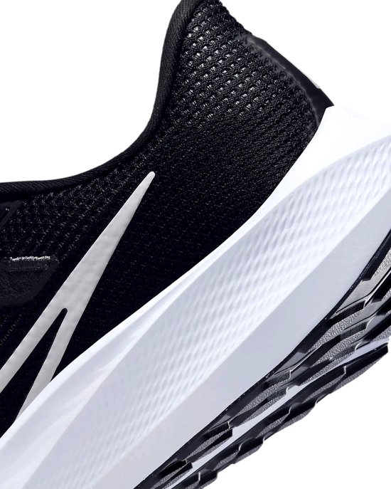Detail van de zijkant van een zwarte Nike hardloopschoen, witte zool met textuur.