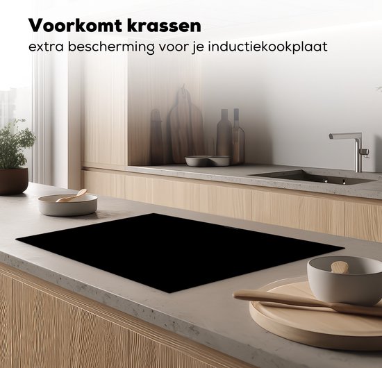 Zwarte inductiebeschermer op een aanrecht in een moderne keuken, naast een spoelbak.