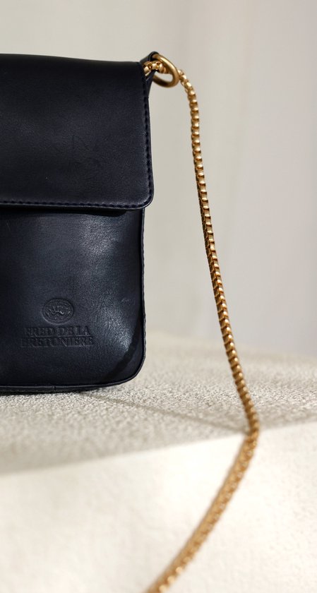 Close-up van de goudkleurige ketting en de zwarte leren Fred de la Bretoniere telefoontas.