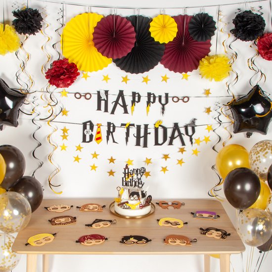 Een feestelijke muurdecoratie met een 'Happy Birthday' banner, ballonnen en papieren waaiers.