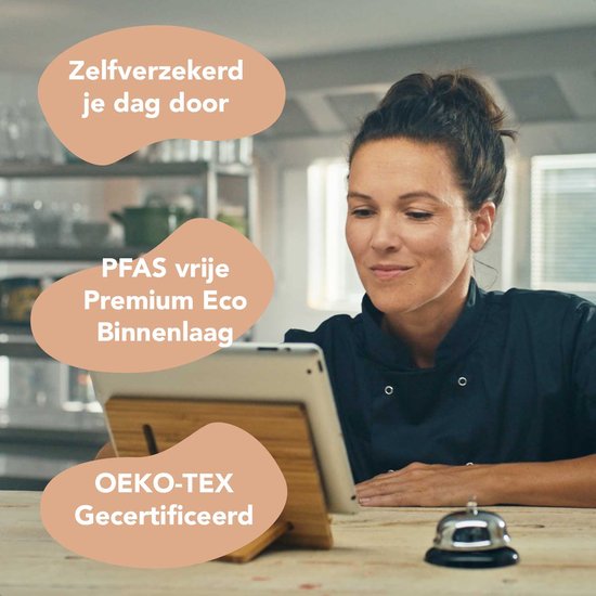 Femme en tenue de travail noire regardant une tablette. Texte: Confiante tout au long de la journée, Couche intérieure Premium Eco sans PFAS, Certifié OEKO-TEX.