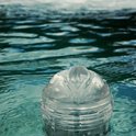 Transparante masturbator met openende lippen, drijvend in helder water.